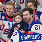 Team USA hockey players Dylan Larkin holding Johnny Gaudreau son Zach Werenski daughter Noa Olympic gold medal celebration February 22 2026