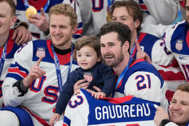 Team USA hockey players Dylan Larkin holding Johnny Gaudreau son Zach Werenski daughter Noa Olympic gold medal celebration February 22 2026
